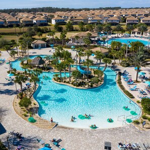 A large swimming pool with multiple lanes, surrounded by lounge chairs and palm trees.