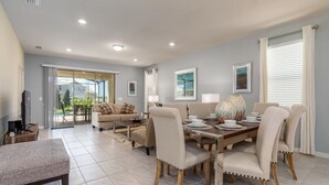 A spacious living room with a dining area, a sofa, and a TV. - Bright Elegant Home at Solterra Resort Sol103 (Davenport)