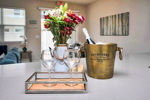 A room with a table set with two wine glasses, a vase with flowers, and a champagne bucket.