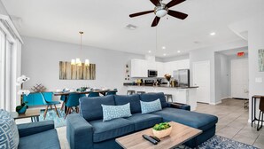 Ein modernes Wohnzimmer mit einem blauen Sofa, einem Holztisch und einem Deckenventilator.