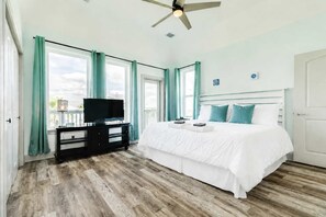 A bedroom with a bed, a TV on a stand, a ceiling fan, and large windows with curtains. - Cyan Sea - Beautiful Sunrises & Sandy Seas, Relax! (Freeport)