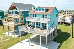 Une maison à deux étages située en bord de mer, dotée d’un balcon, d’une terrasse et d’un patio couvert.