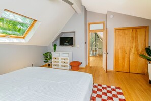 A bedroom with a skylight, a bed, a TV, a wardrobe, and a view of a balcony. - Unique; Modern; Spiral Staircase; Loft; Near IU; Whirlpool Tub; Natural Light (Bloomington)