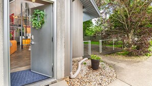 A modern building entrance with a door leading to a room with a blue carpet and a plant. - Unique; Modern; Spiral Staircase; Loft; Near IU; Whirlpool Tub; Natural Light (Bloomington)
