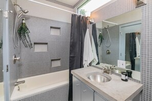 A modern bathroom with a bathtub, a shower, a sink, and a mirror. - Unique; Modern; Spiral Staircase; Loft; Near IU; Whirlpool Tub; Natural Light (Bloomington)