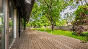 A wooden deck with glass doors leading to a covered outdoor area. - Unique; Modern; Spiral Staircase; Loft; Near IU; Whirlpool Tub; Natural Light (Bloomington)