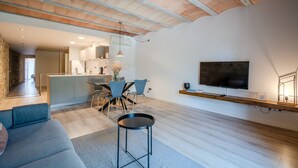 Een moderne woonruimte met een keuken, een eethoek en een aan de muur bevestigde televisie.