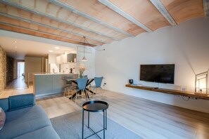 A modern living space with a kitchen, dining area, and a TV mounted on the wall.