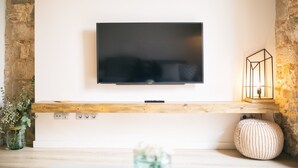 Een flatscreen televisie bevestigd aan een witte muur boven een houten plank.
