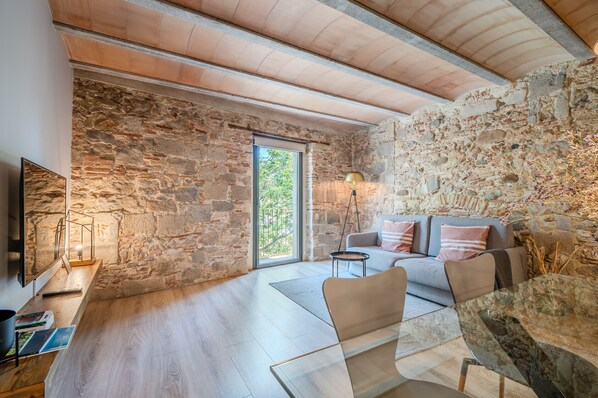 A modern living room with a stone wall, a sofa, a coffee table, and a TV.