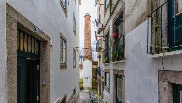 A narrow alleyway between buildings with a brick chimney in the distance. - Hidden Gem in Alfama (Lisbon)