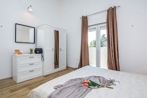 A bedroom with a bed, white wardrobe, and a window with curtains. - Villa Dika Nin (Nin)