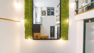 Un comedor con pared verde, un espejo grande y una mesa dispuesta para cuatro.