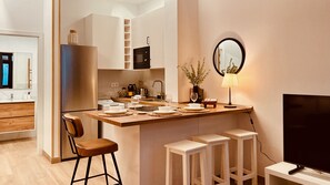 Une cuisine moderne dotée d’un îlot central, de tabourets de bar, d’un téléviseur à écran plat et d’un coin repas.