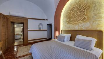 A bedroom with a large bed, a wooden wardrobe, a built-in bathtub, and a decorative wall.