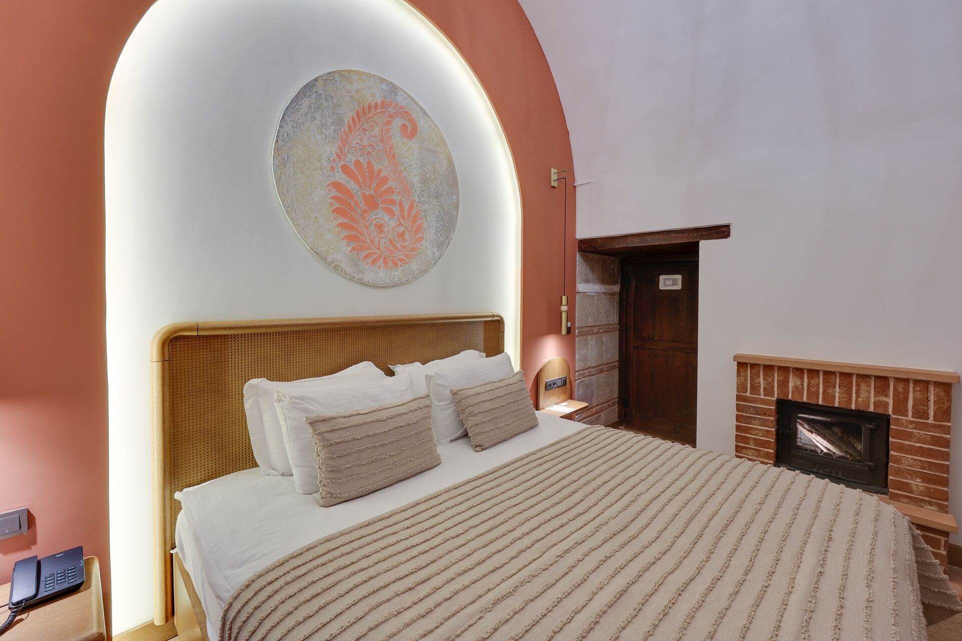 Un dormitorio con cama, una obra de arte en la pared, chimenea y una puerta.