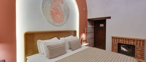 Un dormitorio con cama, una obra de arte en la pared, chimenea y una puerta.