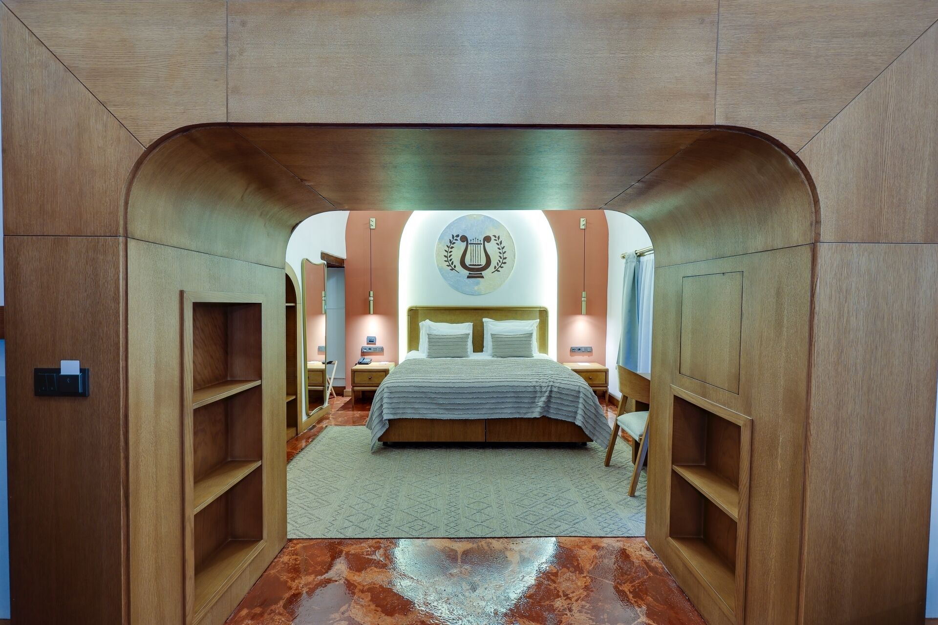 Un dormitorio moderno con cama central, mesitas de noche, un espejo y un adorno en la pared.