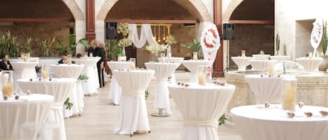 An outdoor venue with multiple round tables covered with white tablecloths, arranged in rows.