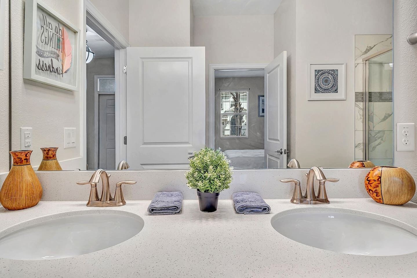Un baño con dos lavamanos, una planta en maceta y jarrones decorativos.