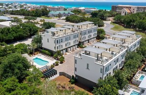 A modern hotel with multiple-story buildings, a swimming pool, and a view of the ocean. - 30A Gem | Rooftop Patio | Heated Pool (Santa Rosa Beach)