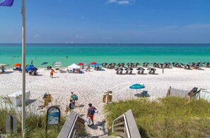 A beach with umbrellas, sun loungers, and a clear view of the ocean.