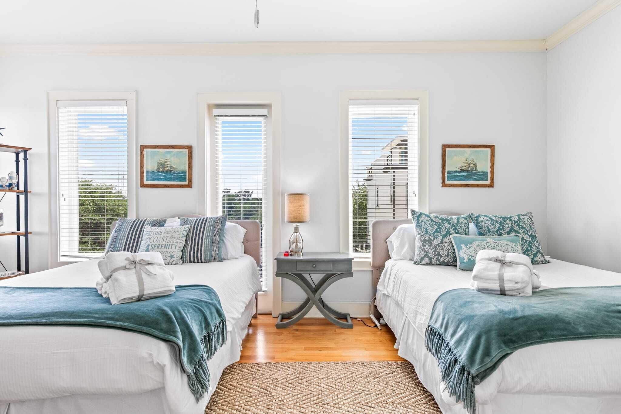 A double room with two beds, a small table, and a view of the sea through large windows.