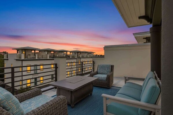 A rooftop terrace with outdoor furniture, a railing, and a view of the buildings in the background.