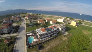 An aerial view of a coastal residential area with houses, a swimming pool, and a view of the sea. - studios Chrysalis (Volvi)