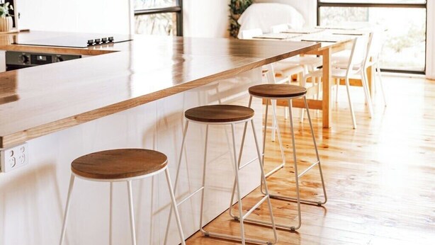 Une cuisine moderne avec des poutres en bois, un long comptoir et des tabourets de bar.