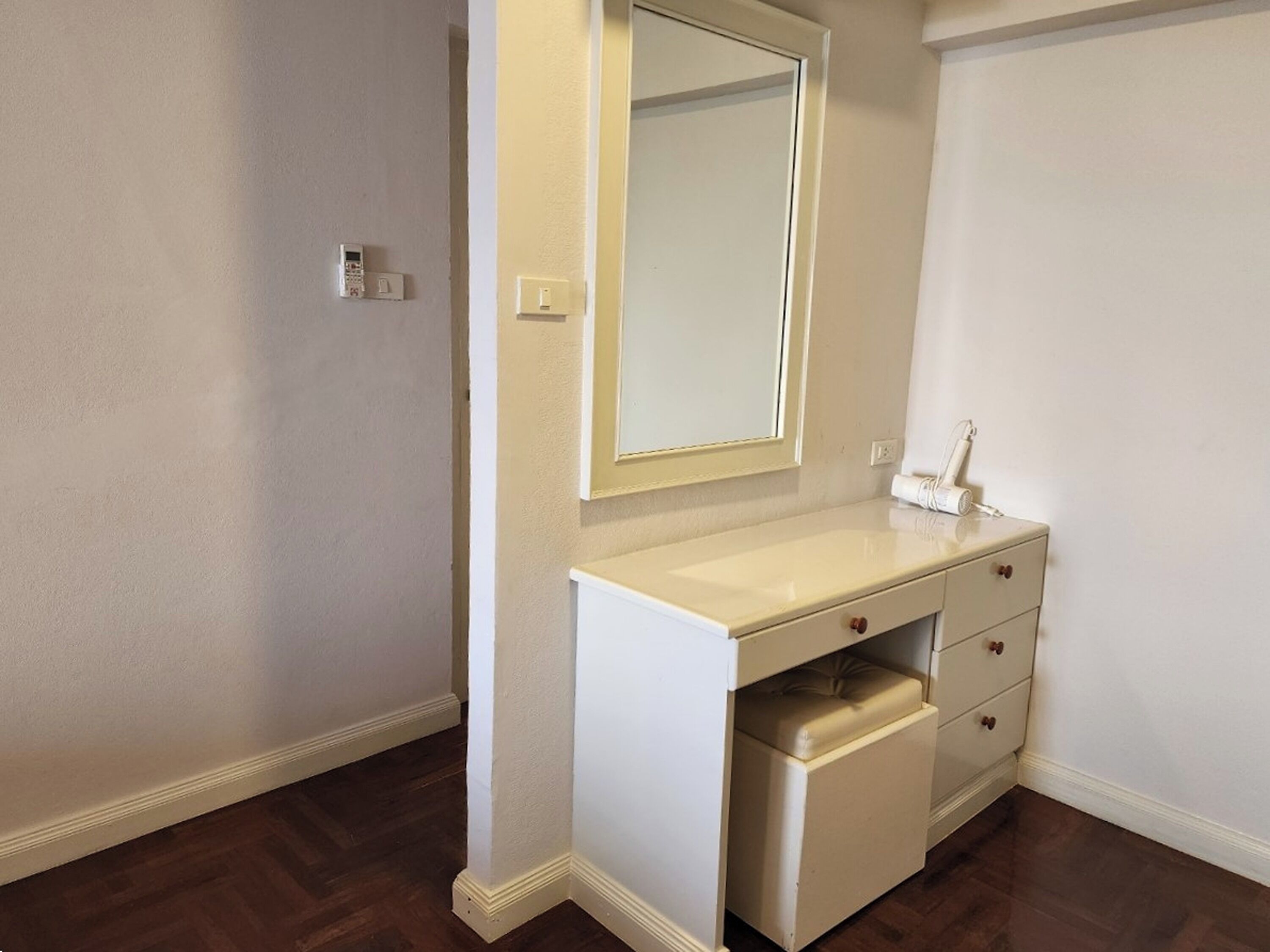 A small, white bathroom with a vanity, a mirror, and a sink.