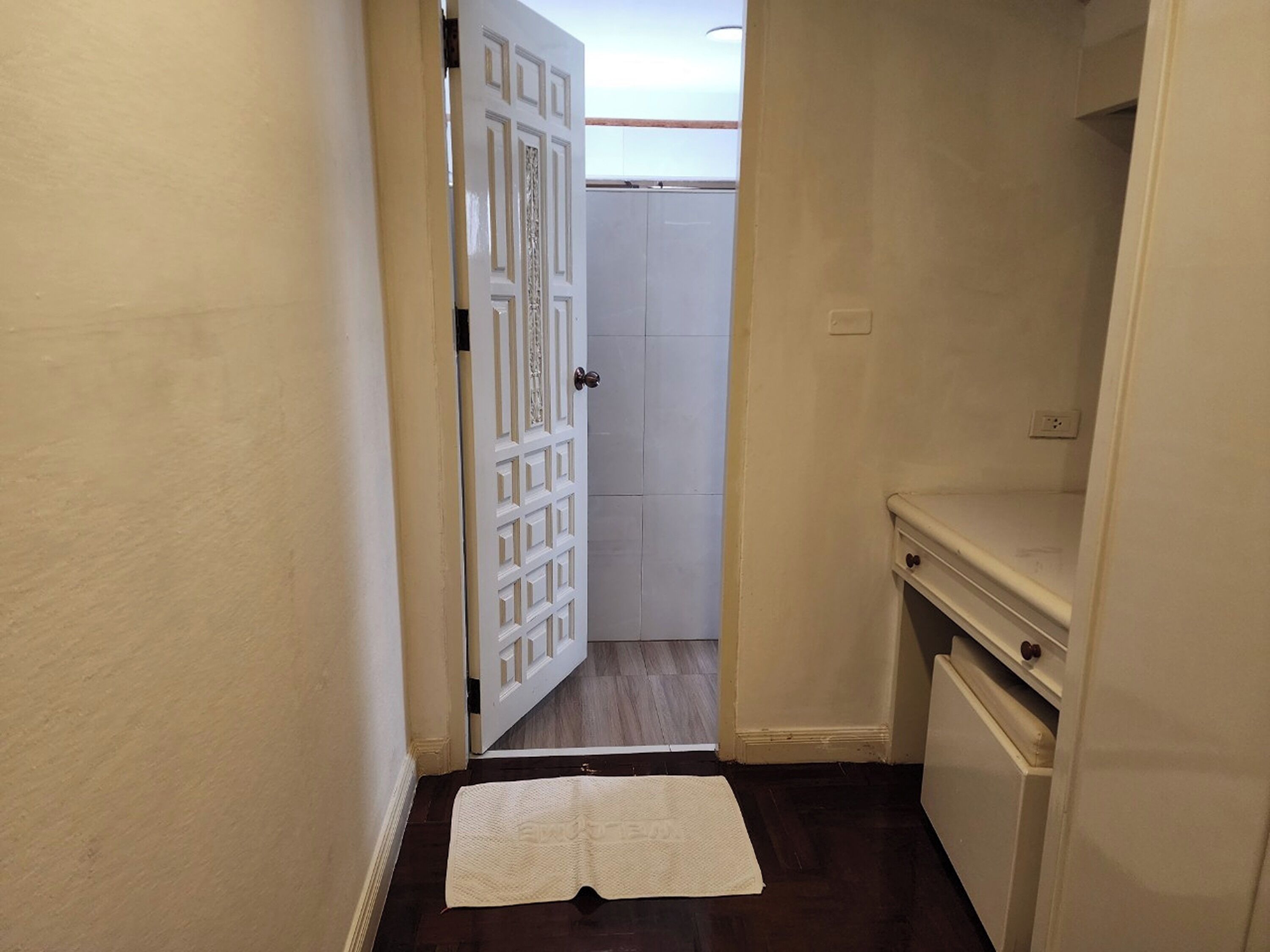 A narrow hallway with a white door leading to a closet.