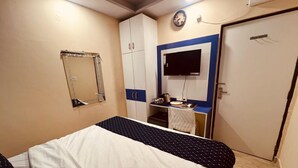 Una camera da letto con un letto, un armadio, una scrivania con un computer e una televisione.