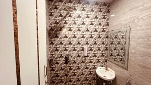 Un bagno con carta da parati decorata, un lavandino e uno specchio.