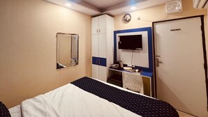 Una camera d'albergo con un letto, una televisione, un armadio e una scrivania con un bollitore.