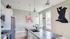 Una cocina moderna con encimera de mármol, electrodomésticos de acero inoxidable e iluminación colgante.