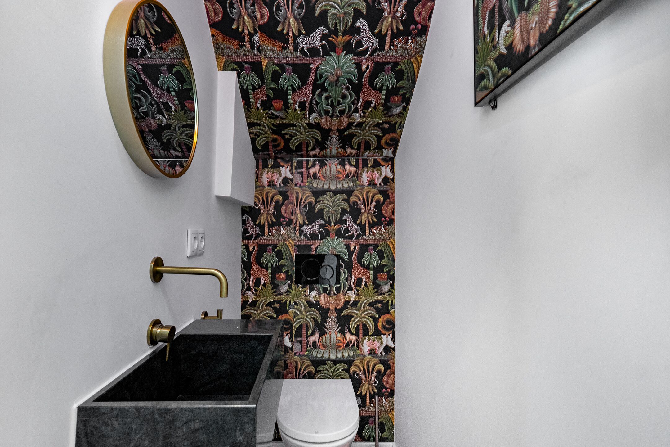 Een badkamer met een zwarte wasbak, een toilet en een spiegel bevestigd aan de muur.