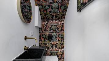 Een badkamer met een zwarte wasbak, een toilet en een spiegel bevestigd aan de muur.