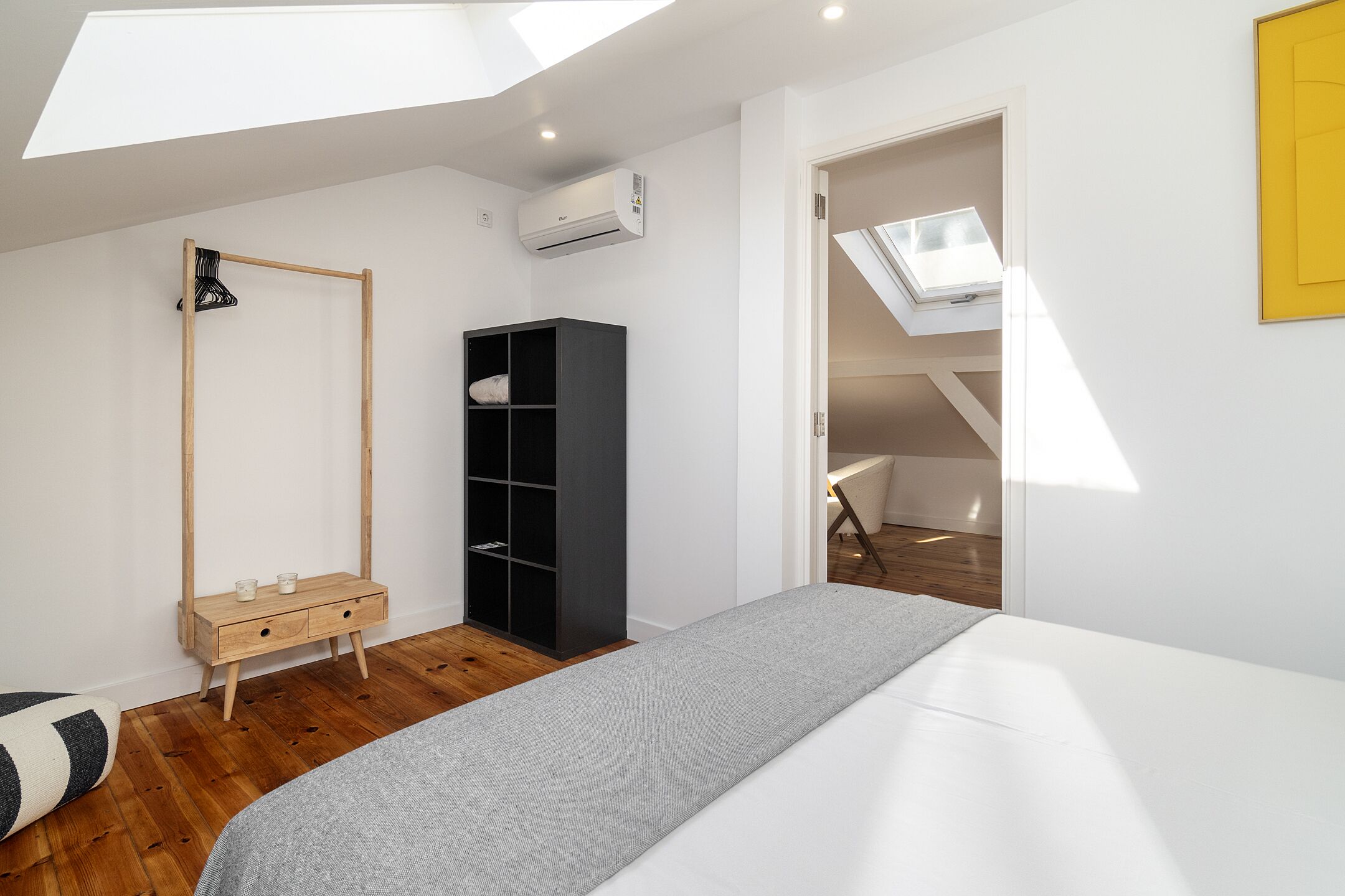 A bedroom with a skylight, a wardrobe, a bedside table, and a bed.