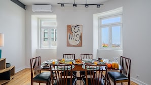 Uma área de refeições com uma mesa redonda, cadeiras e um quadro na parede.