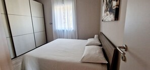 Relax in a stylish space with a neatly made bed, ample storage, and a large wardrobe.