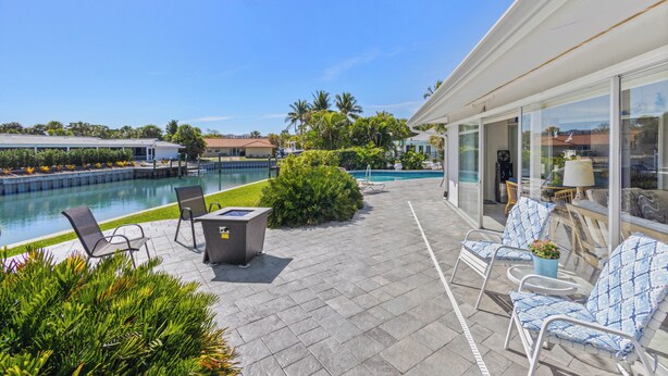 A pool area with lounge chairs, a table, and a glass-enclosed patio. - Tropical Canal Home–Pool, Sun & Water Access: Paradise Cottage in LBK by RVA (Longboat Key)