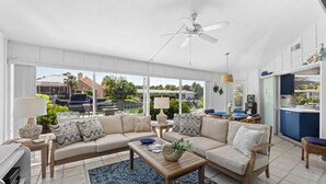 A spacious living area with a sofa, coffee table, and a view of the outdoors. - Tropical Canal Home–Pool, Sun & Water Access: Paradise Cottage in LBK by RVA (Longboat Key)