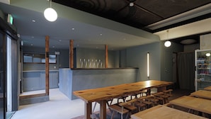 Interior de restaurante con mesas de madera, una zona de bar y un techo con un mural de dragón.