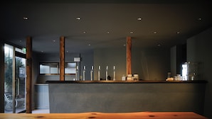 Un interior moderno con una gran mesa de madera, bancos y una encimera con velas y frascos.