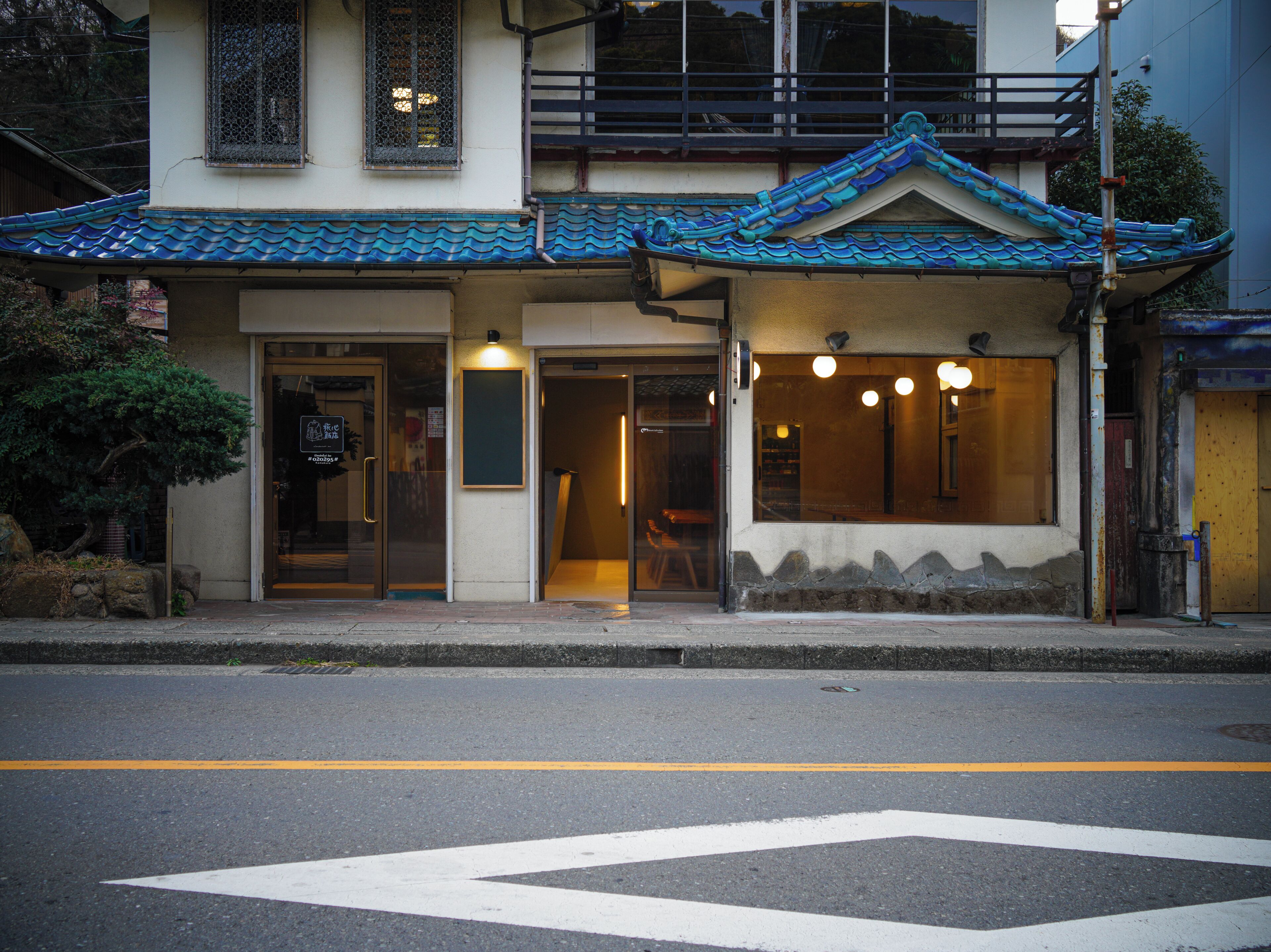 A building with a traditional tiled roof, a visible entrance, and a street in front.