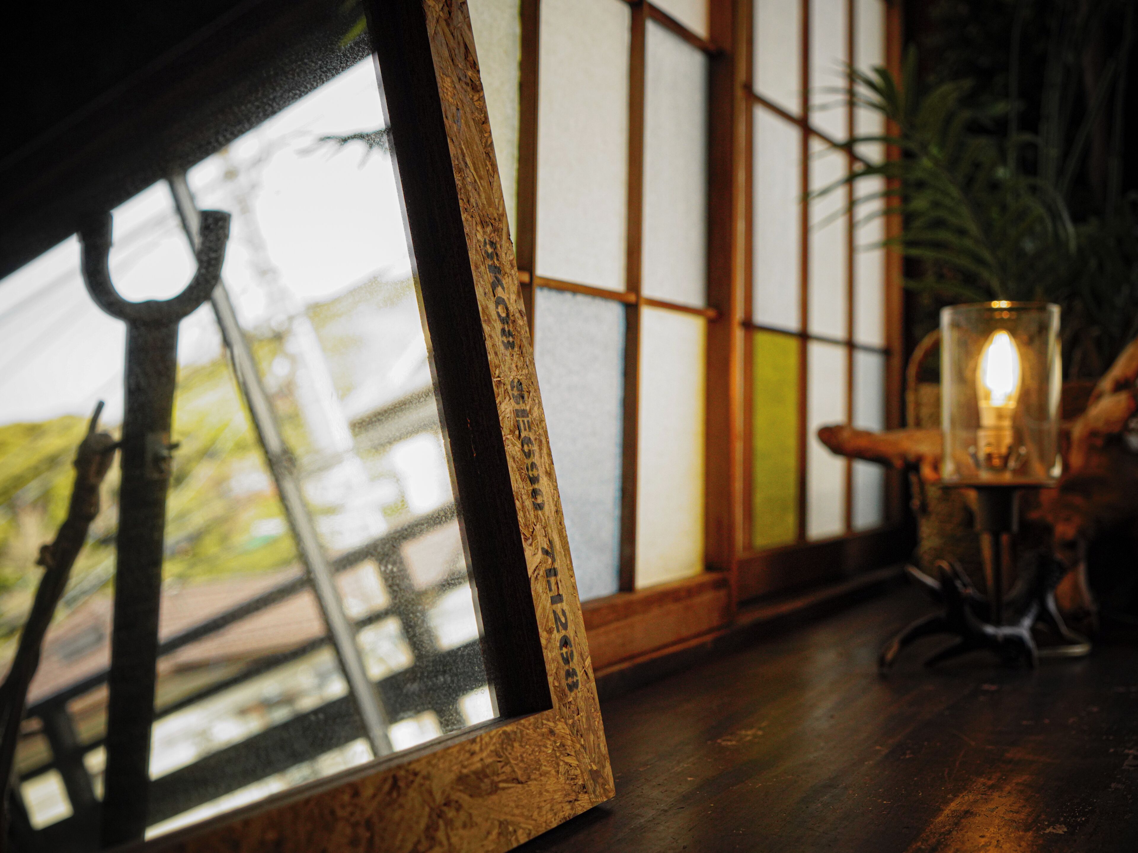 A framed picture with a hook, a candle on a stand, and a traditional Japanese shoji screen in the background.