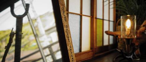 A framed picture with a hook, a candle on a stand, and a traditional Japanese shoji screen in the background.