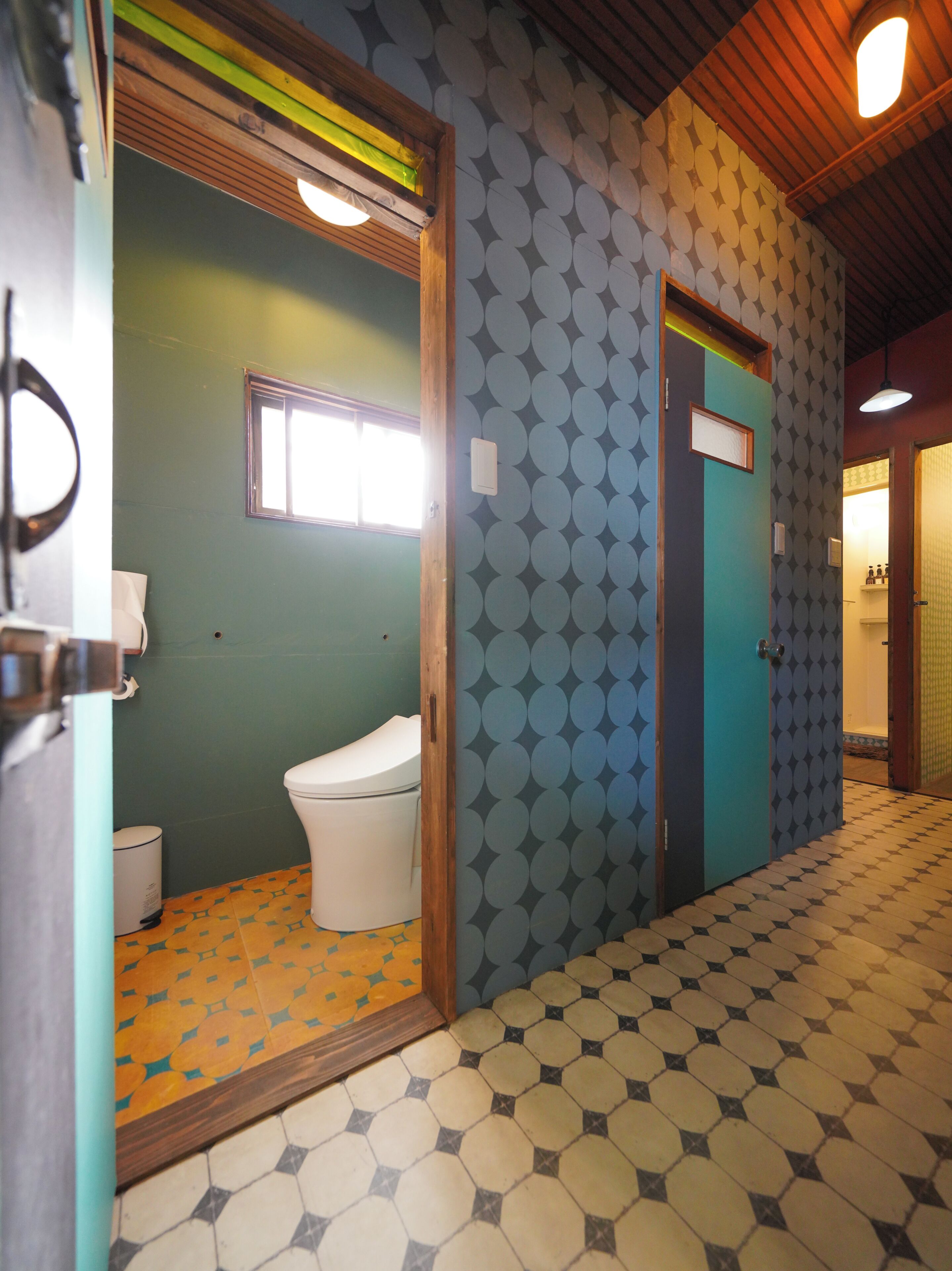 A bathroom with a toilet, a window, and patterned walls.