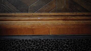 A wooden bench with a geometric patterned wall behind it.